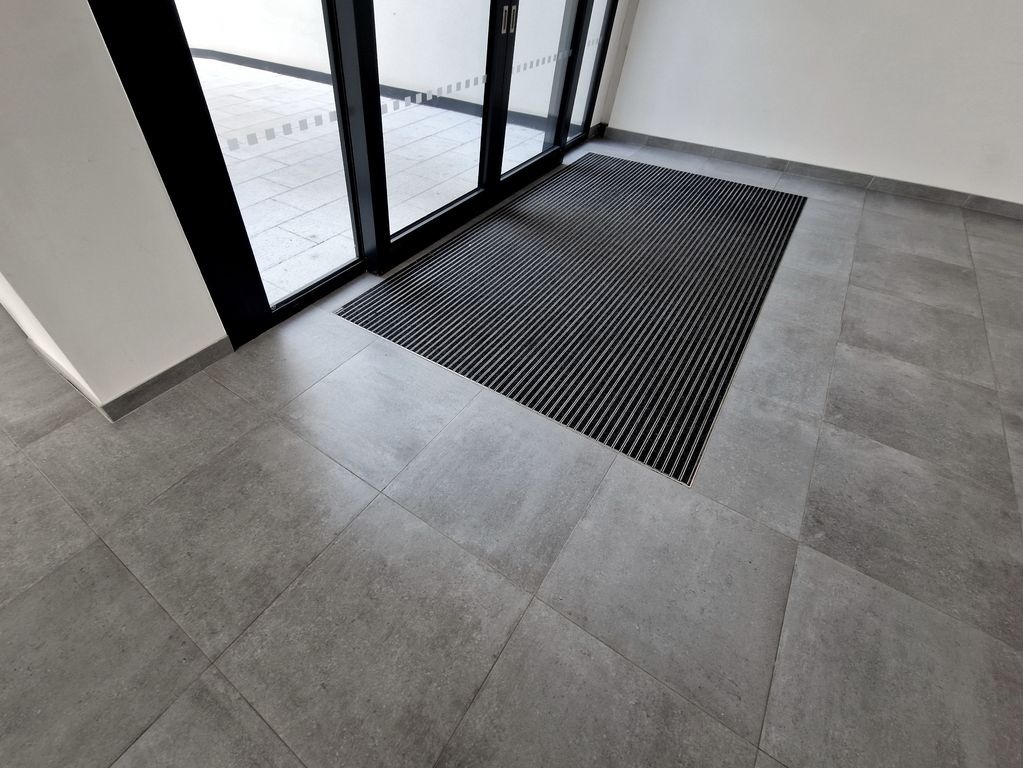 Entree a Saint-Andre-de-Cubzac avec carrelage gris mat et tapis encastre cannele, finition moderne par MC Carreleur.