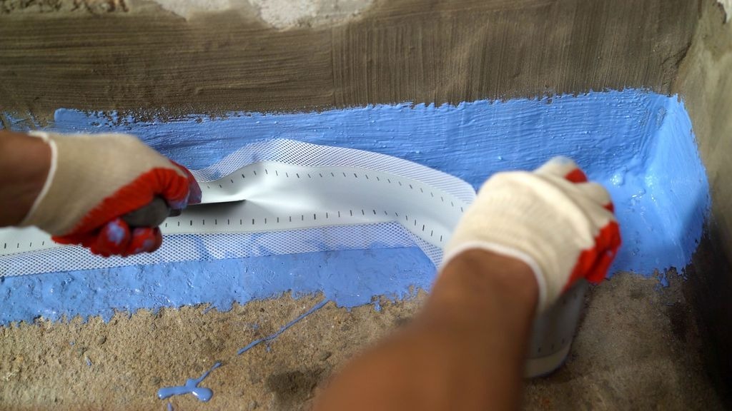 Application d une membrane bleue et bande d etancheite a l angle mur-sol a Izon par MC Carreleur.