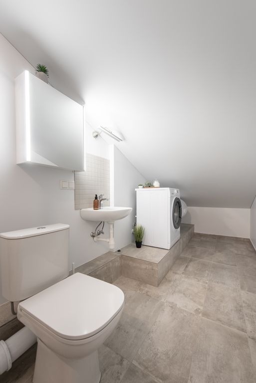 Salle de bain sous combles carrelee en gris grand format a Izon par MC Carreleur, vasque et estrade techniques.