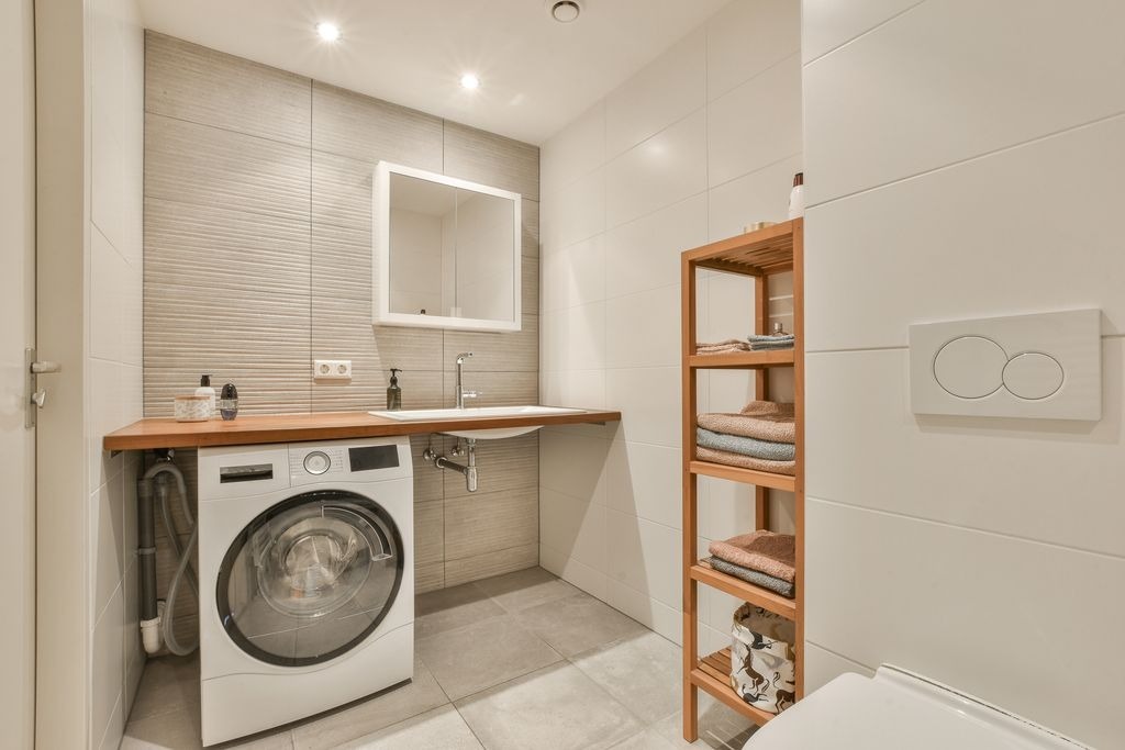 Salle de bain compacte gris-bois a Saint-Andre-de-Cubzac par MC Carreleur : plan bois, mur rainure et lave-linge integre.