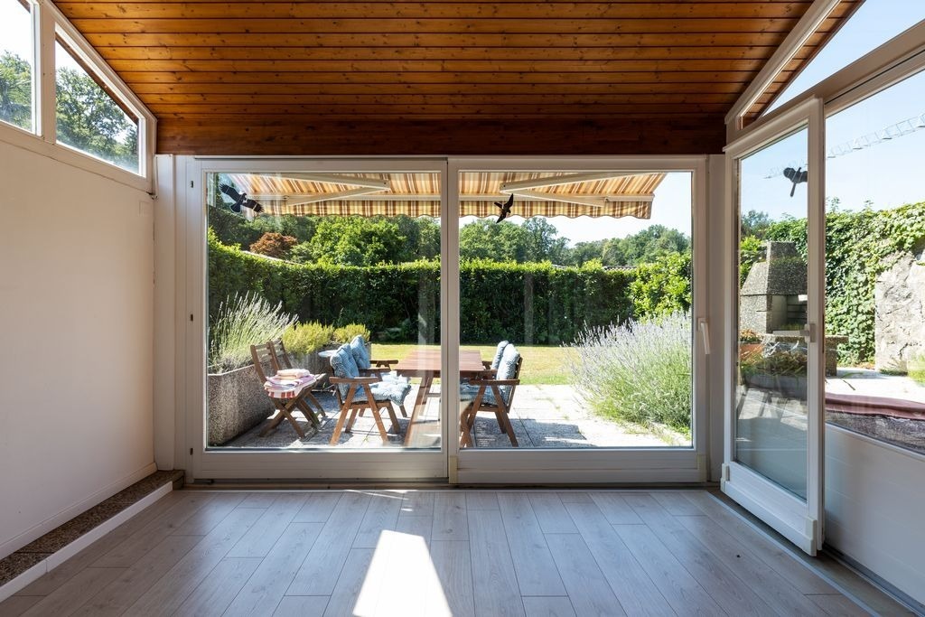 Sol effet parquet en veranda a Bordeaux par MC Carreleur : baies vitrees, terrasse ombragee et jardin fleuri.