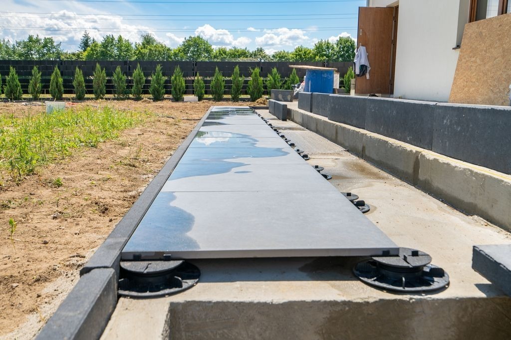 Pose de dalles grises sur plots reglables pour allee de terrasse a Bordeaux par MC Carreleur, en exterieur.