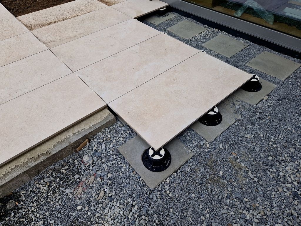 Installation de dalles beige sur plots reglables pour terrasse a Bordeaux par MC Carreleur, sur lit de gravillons.