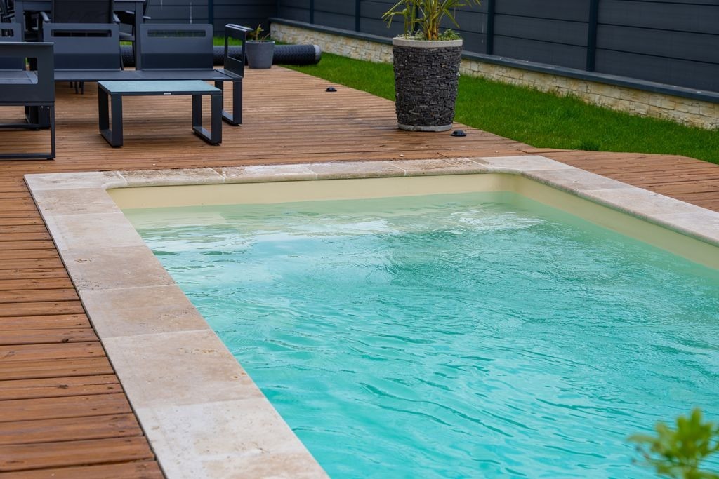 Margelles de piscine en travertin beige et platelage bois a Bordeaux par MC Carreleur, terrasse exterieure.