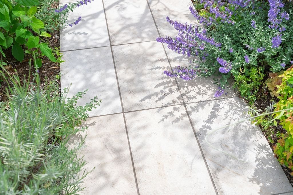 Allee de jardin dallee en dalles beiges a Izon par MC Carreleur, bordee de vegetation et fleurs.