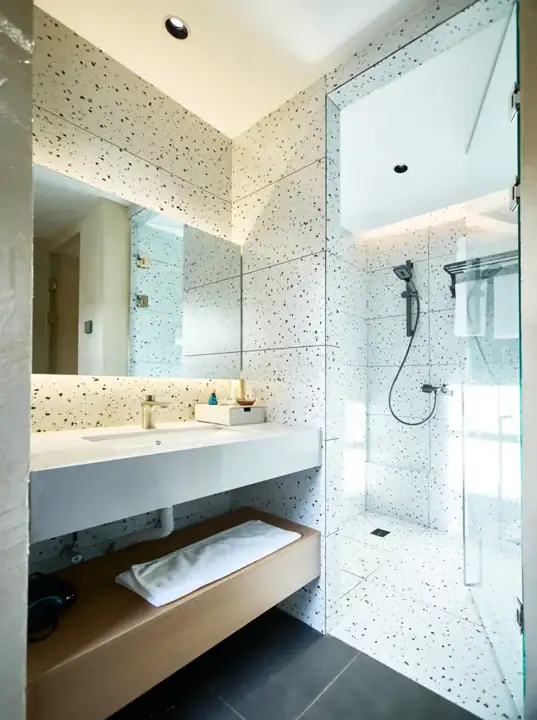Salle de bain avec murs en terrazzo, douche vitrée et vasque